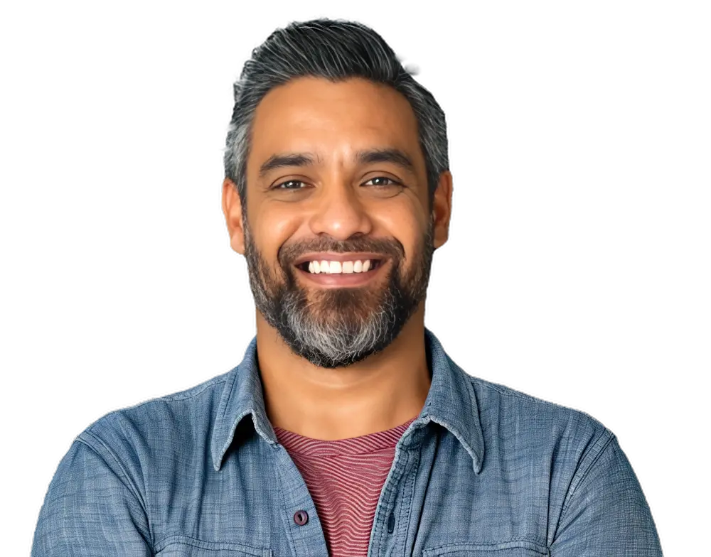 A confident, smiling man with a beard wearing a denim shirt
