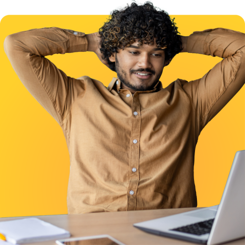 Affordable STI Testing & PrEP Access Smiling man with curly hair stretching while looking at his laptop, representing the ease and affordability of STI testing with Q Care Plus.